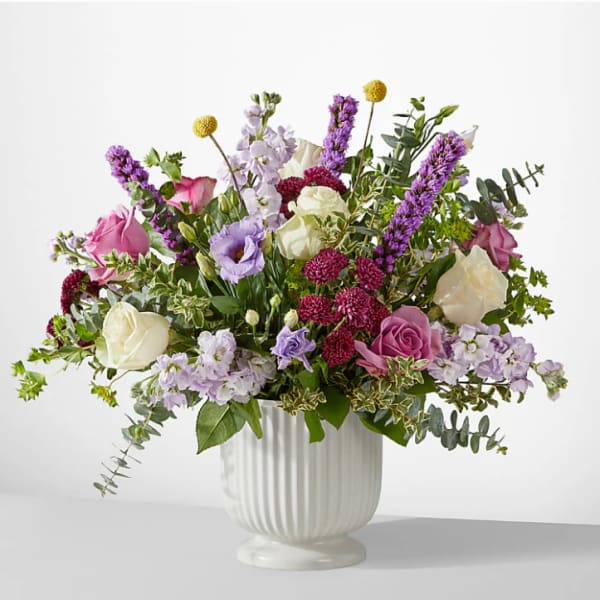 Mixed bouquet of pink, white, and purple flowers in a white vase