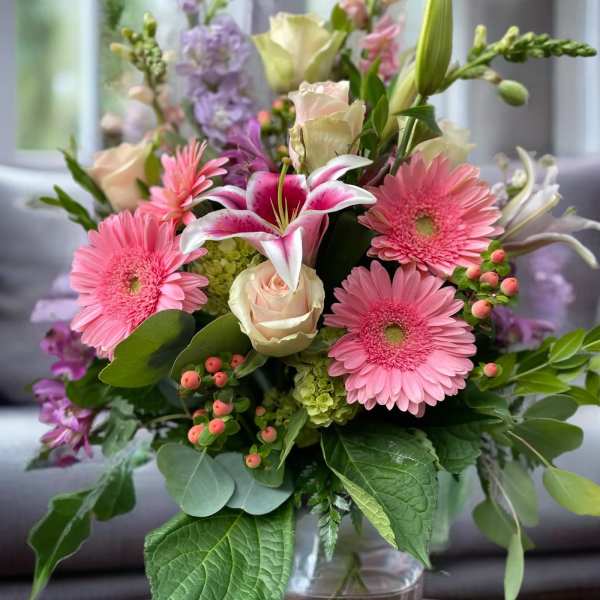 Pink gerbera daisies, lilies, and roses in a glass vase