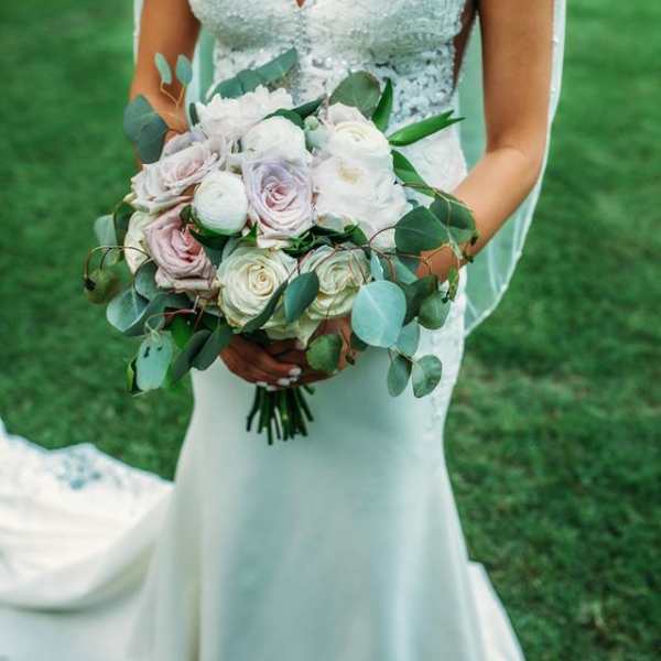 Bride holding a bouquet of pale roses and greenery