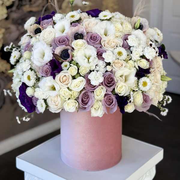 Mixed bouquet of roses and white daisies in a pink cylindrical box