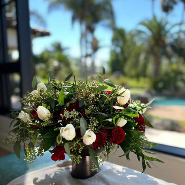 Red and white rose arrangement in a dark vase