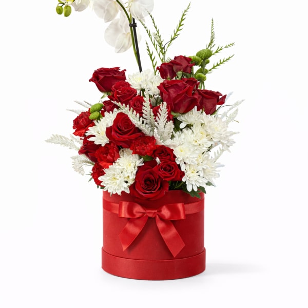 Red roses and white flowers in a red hat box with a white orchid stem