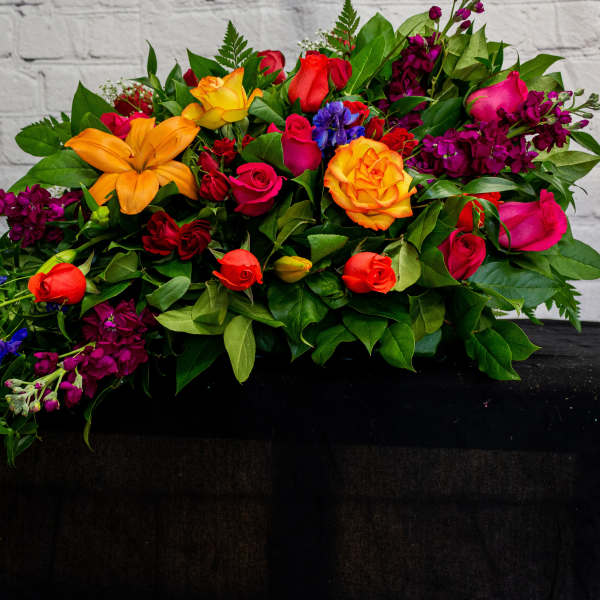 Colorful mixed bouquet with roses and lilies on a dark cloth