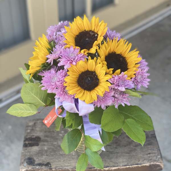 Bouquet of sunflowers and purple chrysanthemums tied with a lavender ribbon