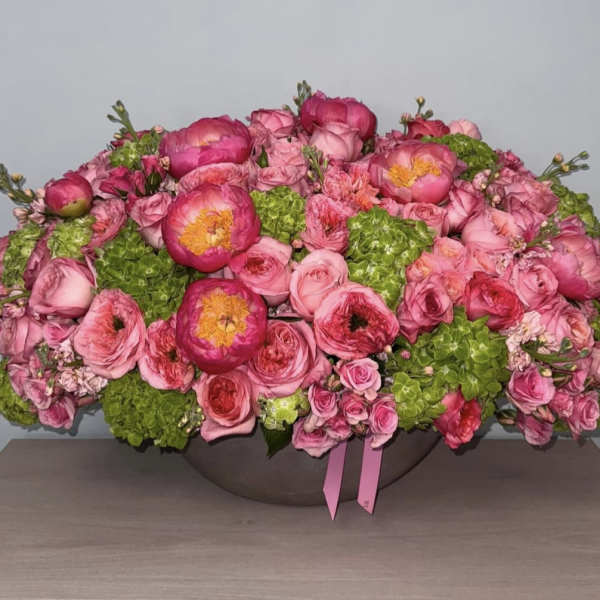 Pink floral arrangement with roses and peonies in a low bowl