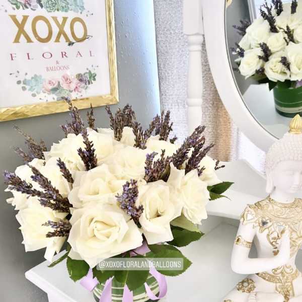 White rose bouquet in a striped vase with purple accents