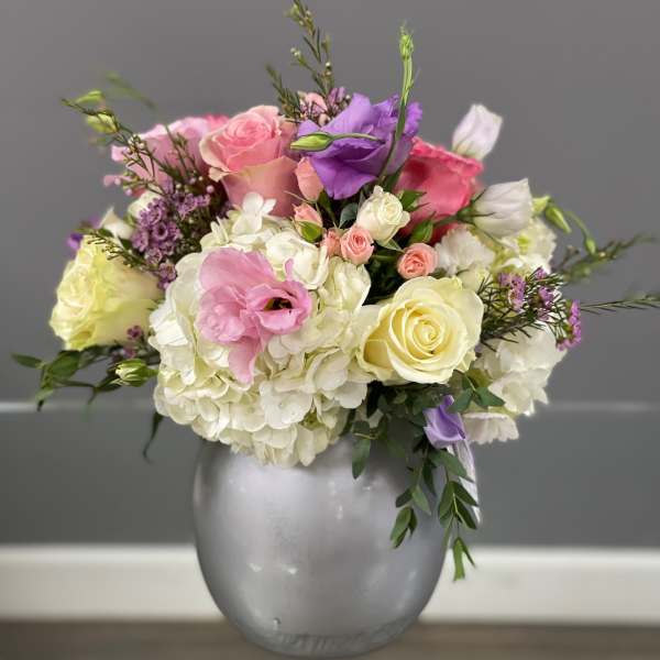 Mixed pink, white, and purple flowers arranged in a silver vase
