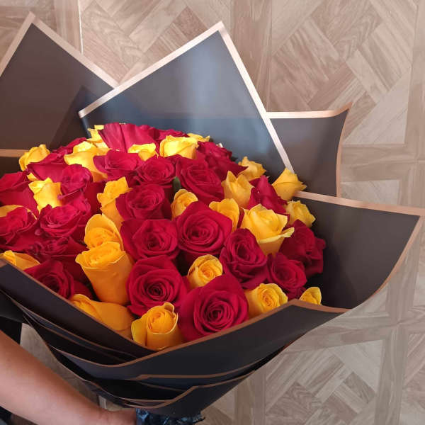 Bouquet of red and yellow roses wrapped in black paper