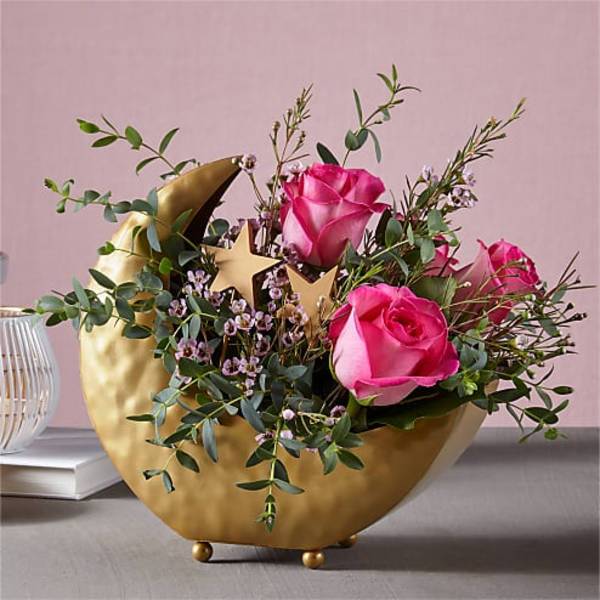 Pink roses in a gold crescent vase with greenery and star accents
