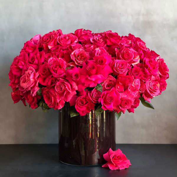 Large bouquet of hot pink roses in a dark glass vase