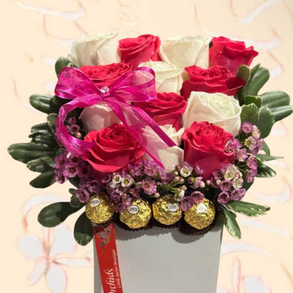 Pink and white roses in a square box with a ribbon and chocolates