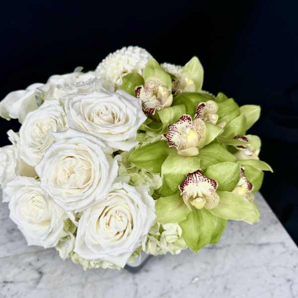 White roses and green orchids arranged in a low bouquet