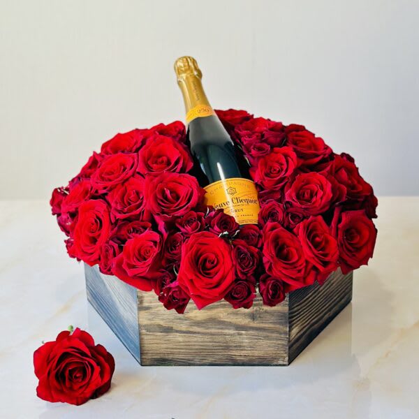 Red roses arranged around a champagne bottle in a wooden box