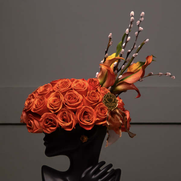 Orange rose arrangement in a black bust vase with pussy willow stems