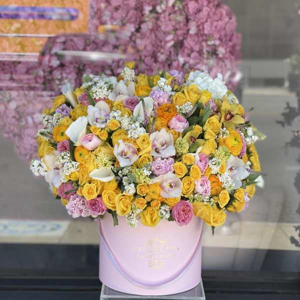 Large pastel bouquet of yellow, pink, and white flowers in a pink hat box