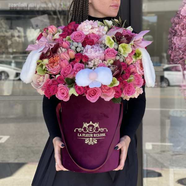 Large pink floral arrangement in a burgundy hatbox with white plush ears
