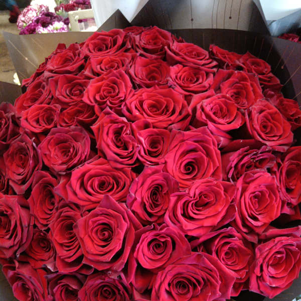 Large bouquet of red roses wrapped in dark paper