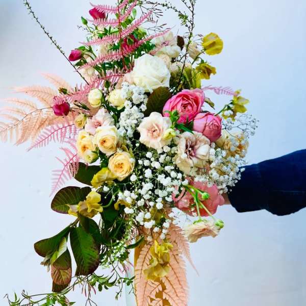 Handheld bouquet of pink and cream roses with airy filler flowers