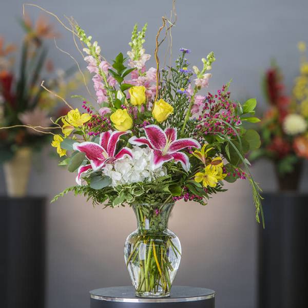 Mixed bouquet with lilies, roses, and snapdragons in a clear glass vase