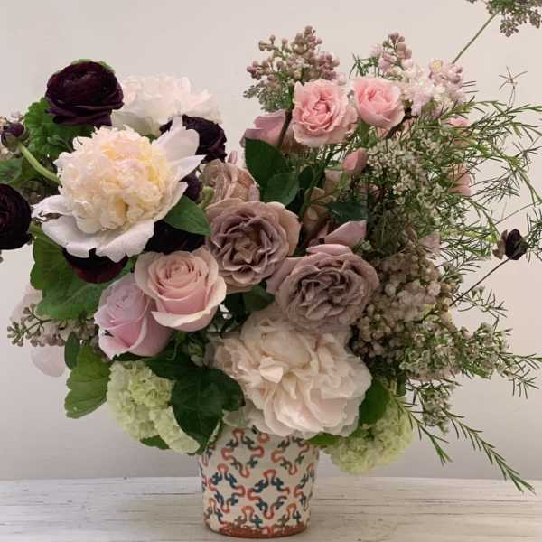 Mixed pink and cream floral arrangement in a patterned vase