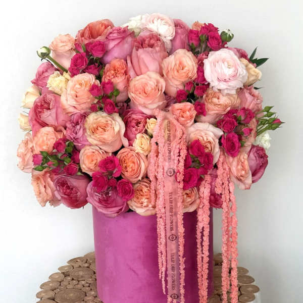 Pink and peach rose bouquet in a magenta hat box with trailing ribbons