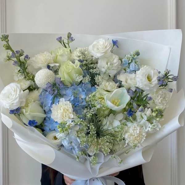 Bouquet of white and blue flowers wrapped in white paper