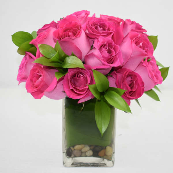 Bouquet of bright pink roses in a square glass vase