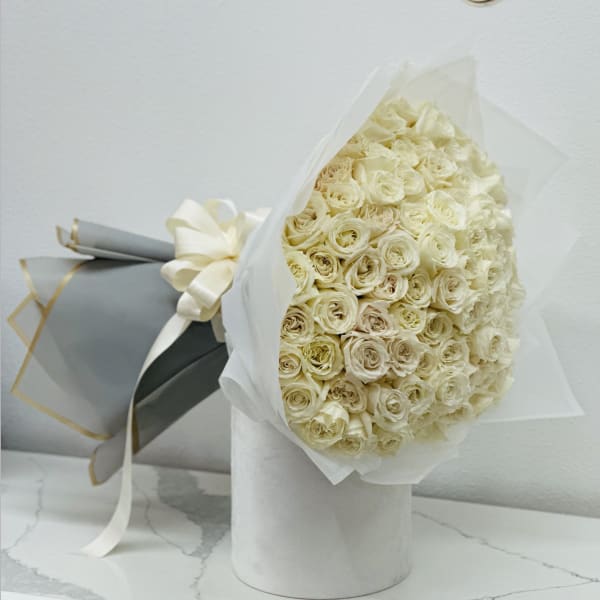 Bouquet of cream roses wrapped in white paper with a ribbon