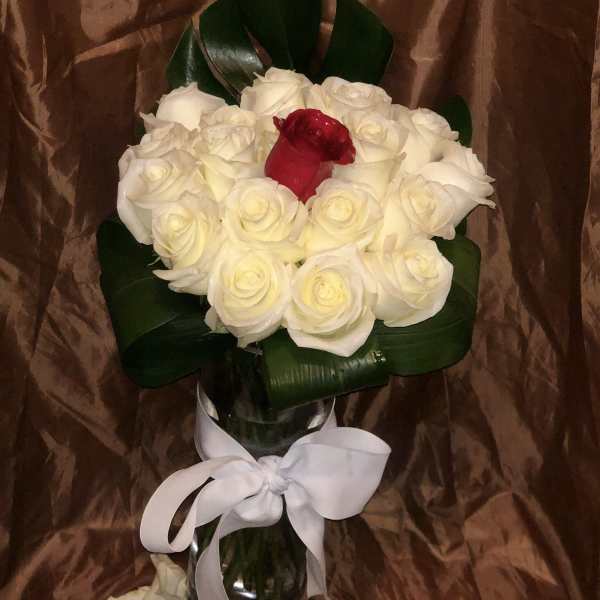 Bouquet of white roses with one red rose in a glass vase