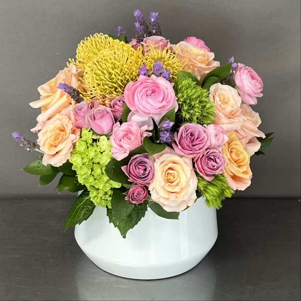 Mixed pink and peach roses in a white vase with yellow blooms