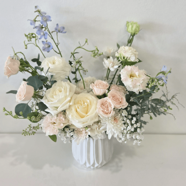 Pastel bouquet of roses and mixed blooms in a white vase
