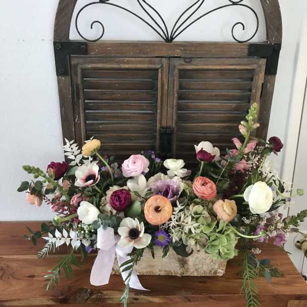 Mixed pastel flower arrangement in a rustic rectangular container