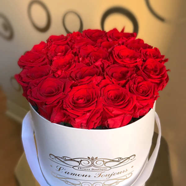 Round white box filled with tightly packed red roses