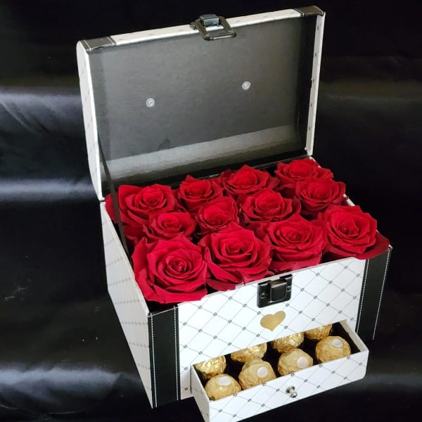 Open gift box with red roses and gold-wrapped chocolates