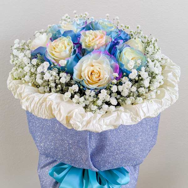 Bouquet of pastel roses with baby's breath in blue wrapping