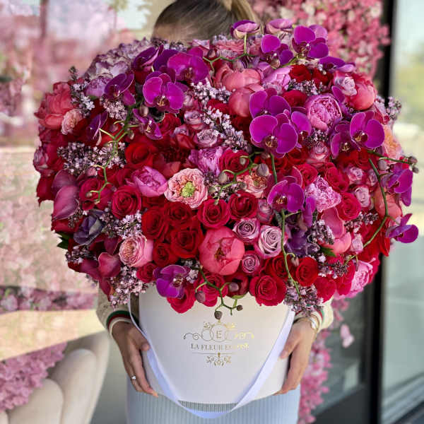 Large pink and red flower arrangement in a white hat box