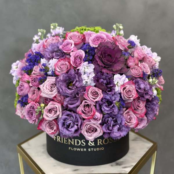 Round box arrangement of pink and purple roses and lisianthus