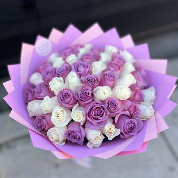 Bouquet of pink, purple, and white roses wrapped in pink paper