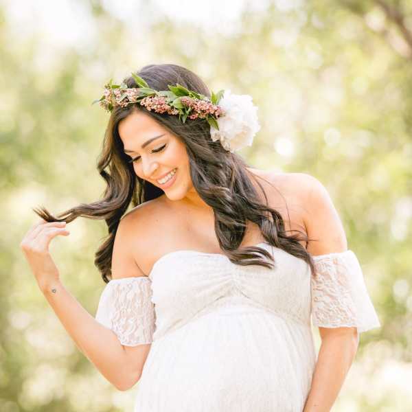 Pregnant woman in a white dress wearing a floral crown
