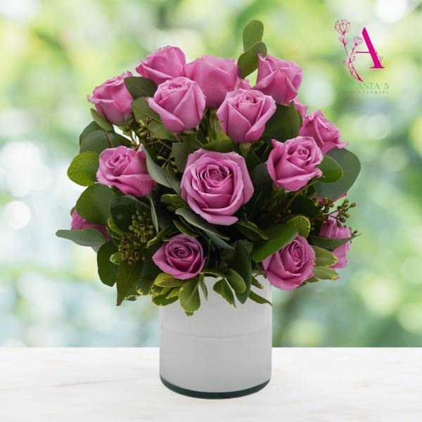 Pink roses arranged in a white vase with green foliage