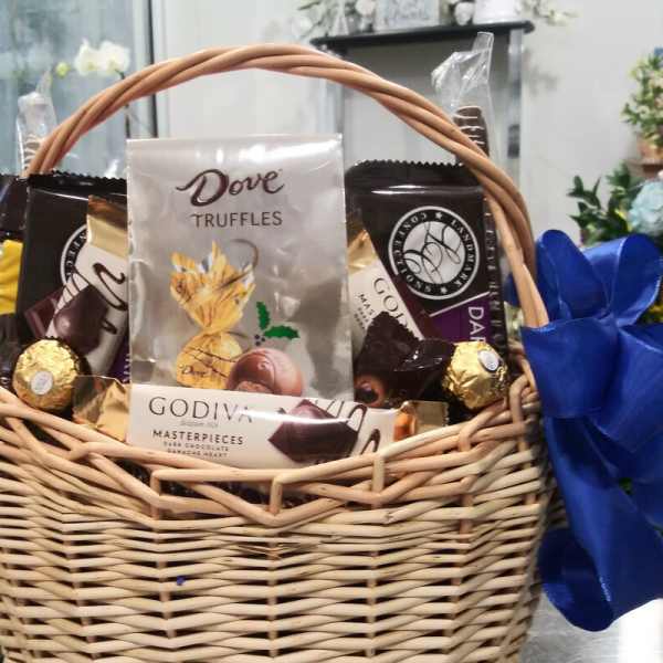 Wicker basket filled with assorted chocolates and a blue ribbon bow