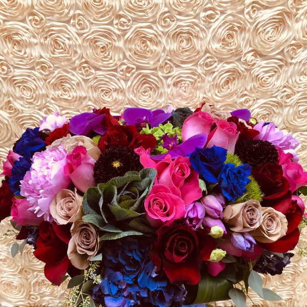 Large mixed bouquet of roses, orchids, and hydrangeas in a blue vase
