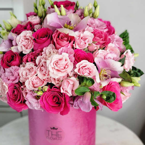 Pink and magenta roses arranged in a round pink box
