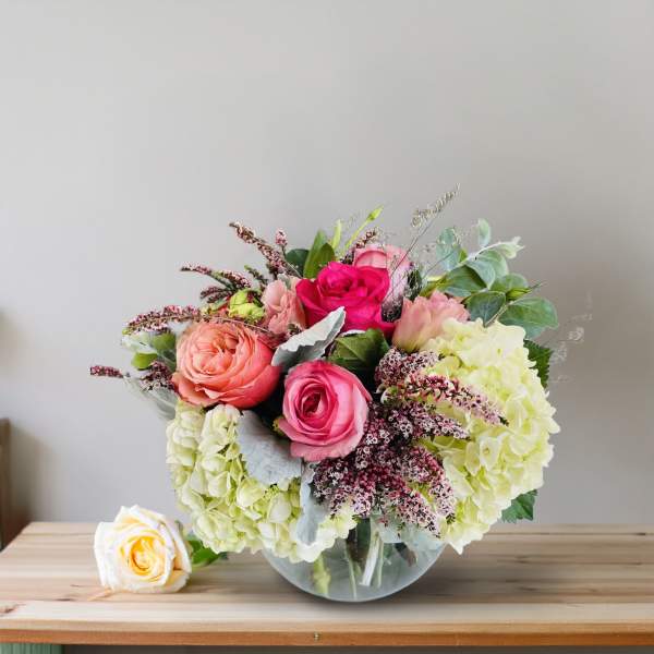 Bouquet of pink and peach roses with pale hydrangeas in a glass vase