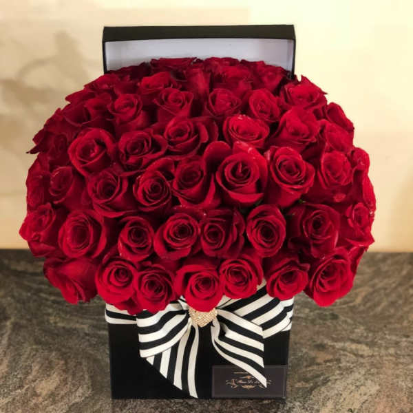 Boxed arrangement of red roses with a black-and-white striped ribbon