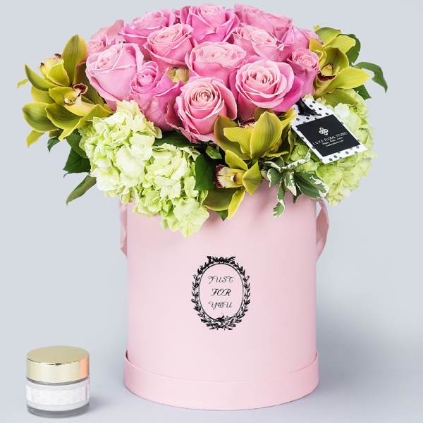 Pink roses and green orchids in a pink hat box with a small candle jar
