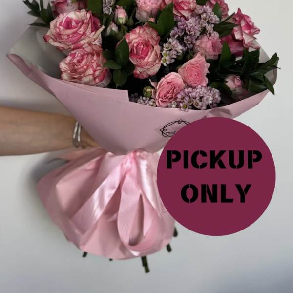 Pink rose bouquet wrapped in pink paper with a satin ribbon