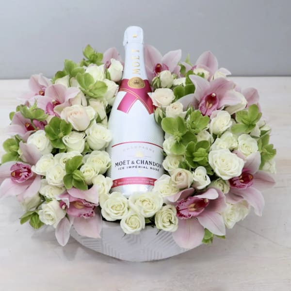 Floral arrangement around a champagne bottle with pink orchids and white roses
