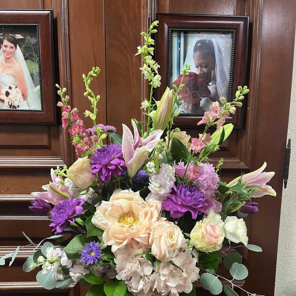 Mixed bouquet of pink, purple, and cream flowers in a glass vase