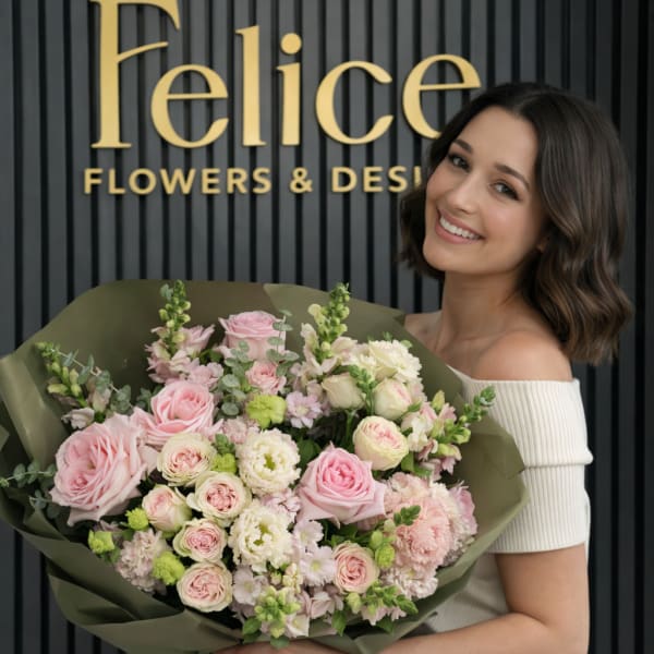 Woman holding a large bouquet of pink and white flowers wrapped in green paper